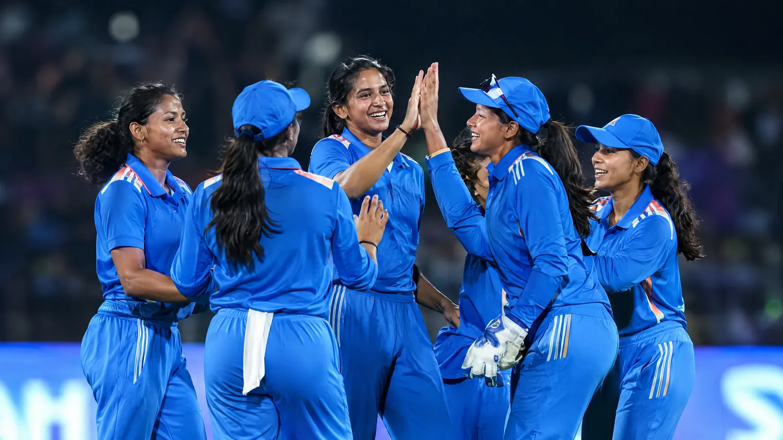 Indian women cricketers in blue training under floodlights before a T20 match